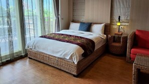 A neatly arranged bedroom with a large bed, a bedside table with a lamp, and a wicker chair. - Jimei Homestay (Ji'an)
