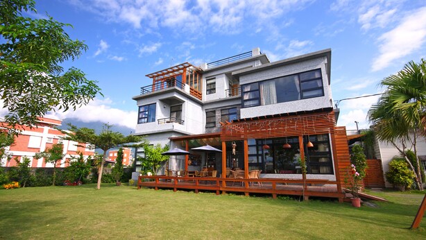 A modern multi-story house with a spacious outdoor patio area, large windows, and a well-maintained lawn. - Jimei Homestay (Ji'an)