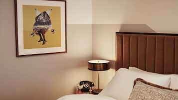 A hotel room with a bed, a nightstand with a lamp, a framed picture, and a brown headboard.