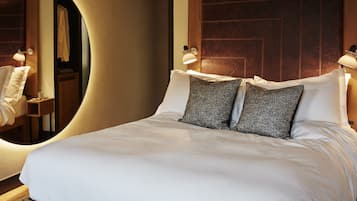 Una cama bien hecha con dos almohadas, un cabecero de madera y dos lámparas de noche.