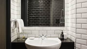 Un baño con un lavabo blanco, encimera negra y un espejo encima.