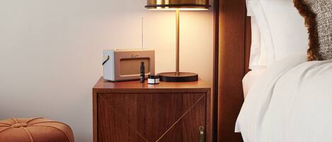 Ein ordentlich eingerichtetes Schlafzimmer mit einem Bett, einem Nachttisch mit Lampe, einem Radio und einem kleinen Schrank.