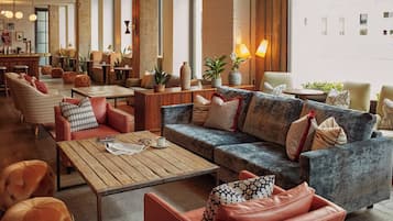 A modern lounge area with seating arrangements, a wooden table, and decorative plants.