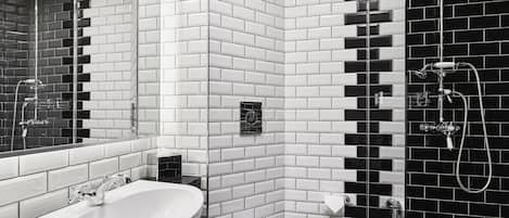 A modern bathroom with a white and black tiled wall, a large mirror, a sink, and a shower area.