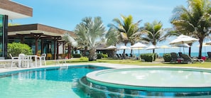 Una piscina al aire libre, sombrillas, sillones reclinables de piscina