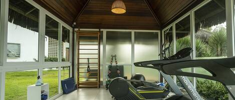 Ein Heim-Fitnessraum mit Laufband, Ergometer und Klimmzugstange.