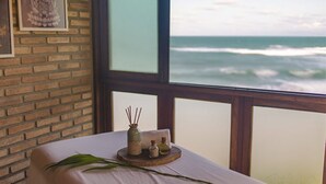 Een kamer met uitzicht op de oceaan, een massagetafel en een klein dienblad met spullen.