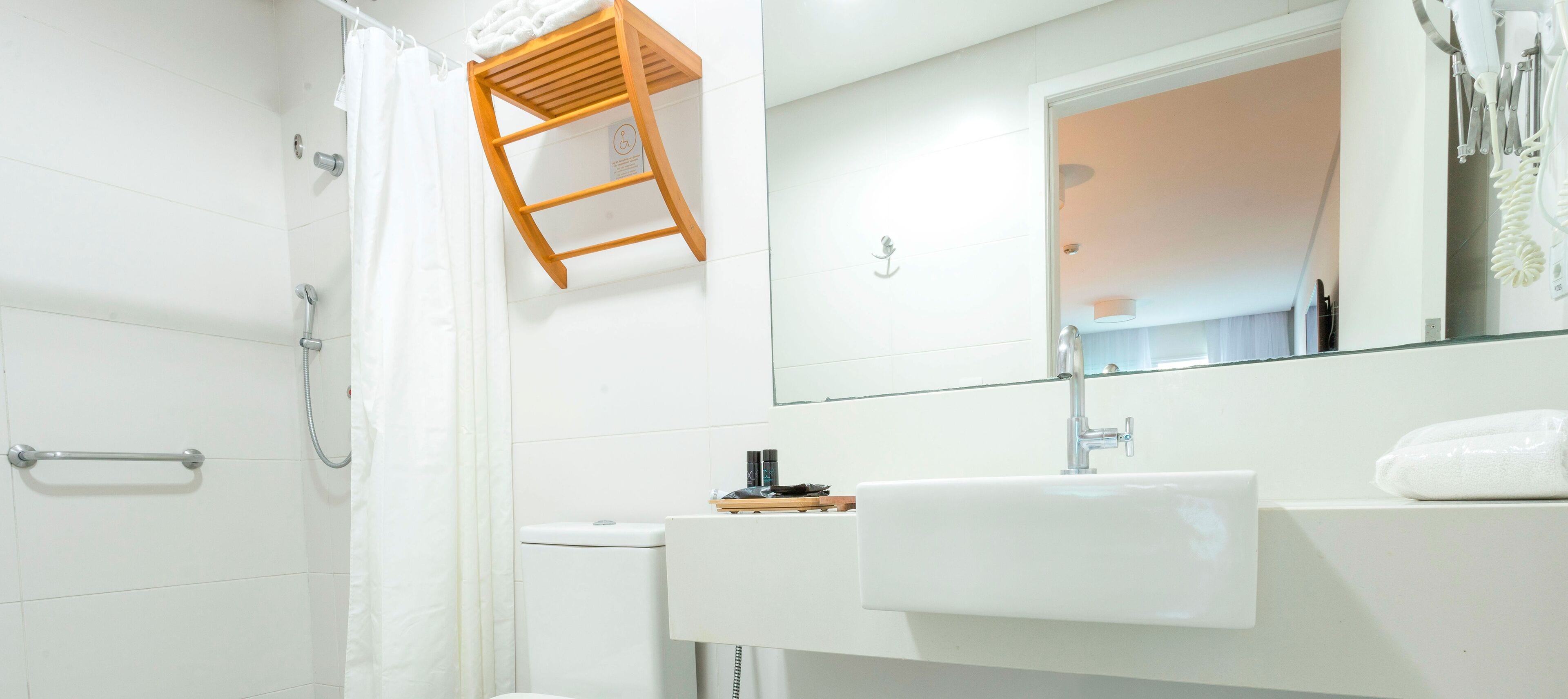 A bathroom with a shower, toilet, sink, and a towel rack.