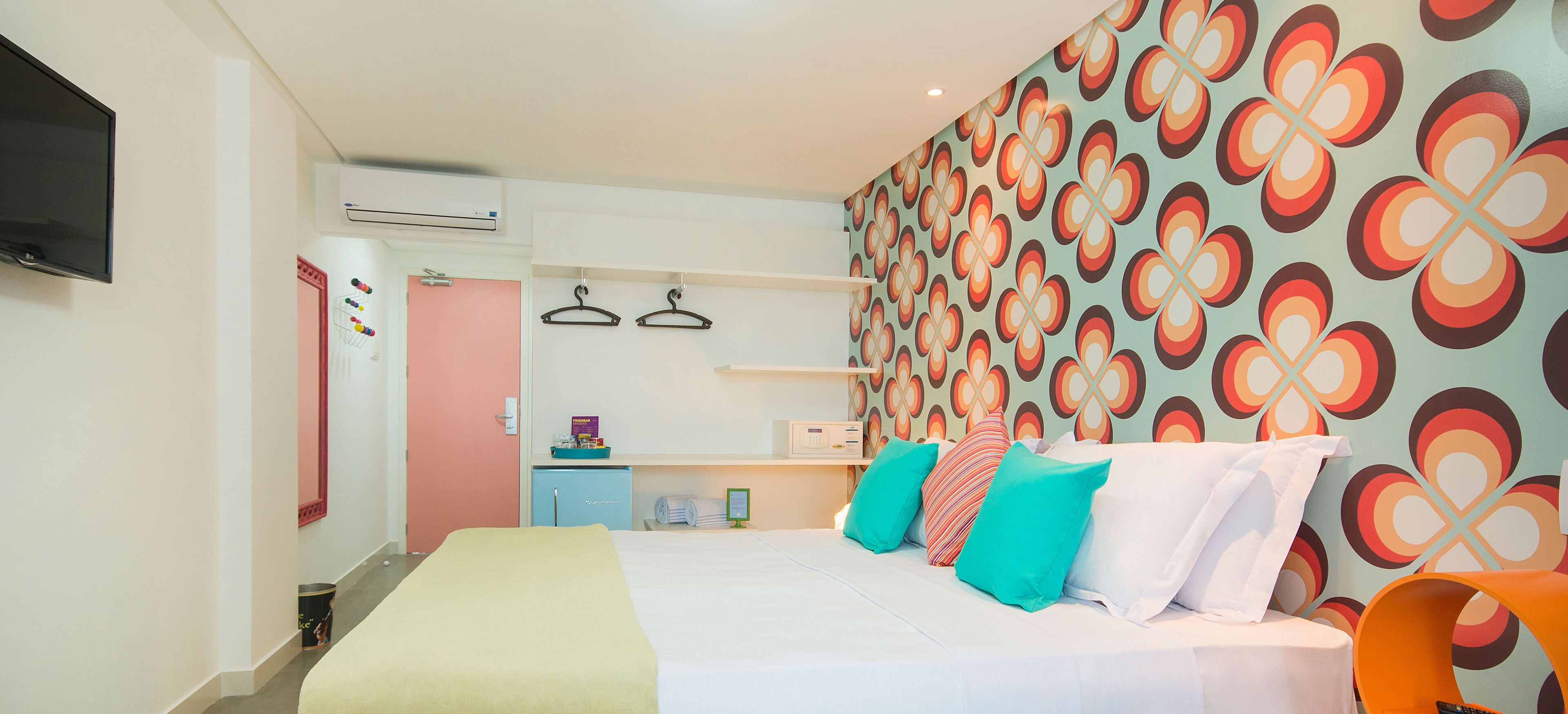A hotel room with a bed, a TV, a wardrobe, and a bathroom.