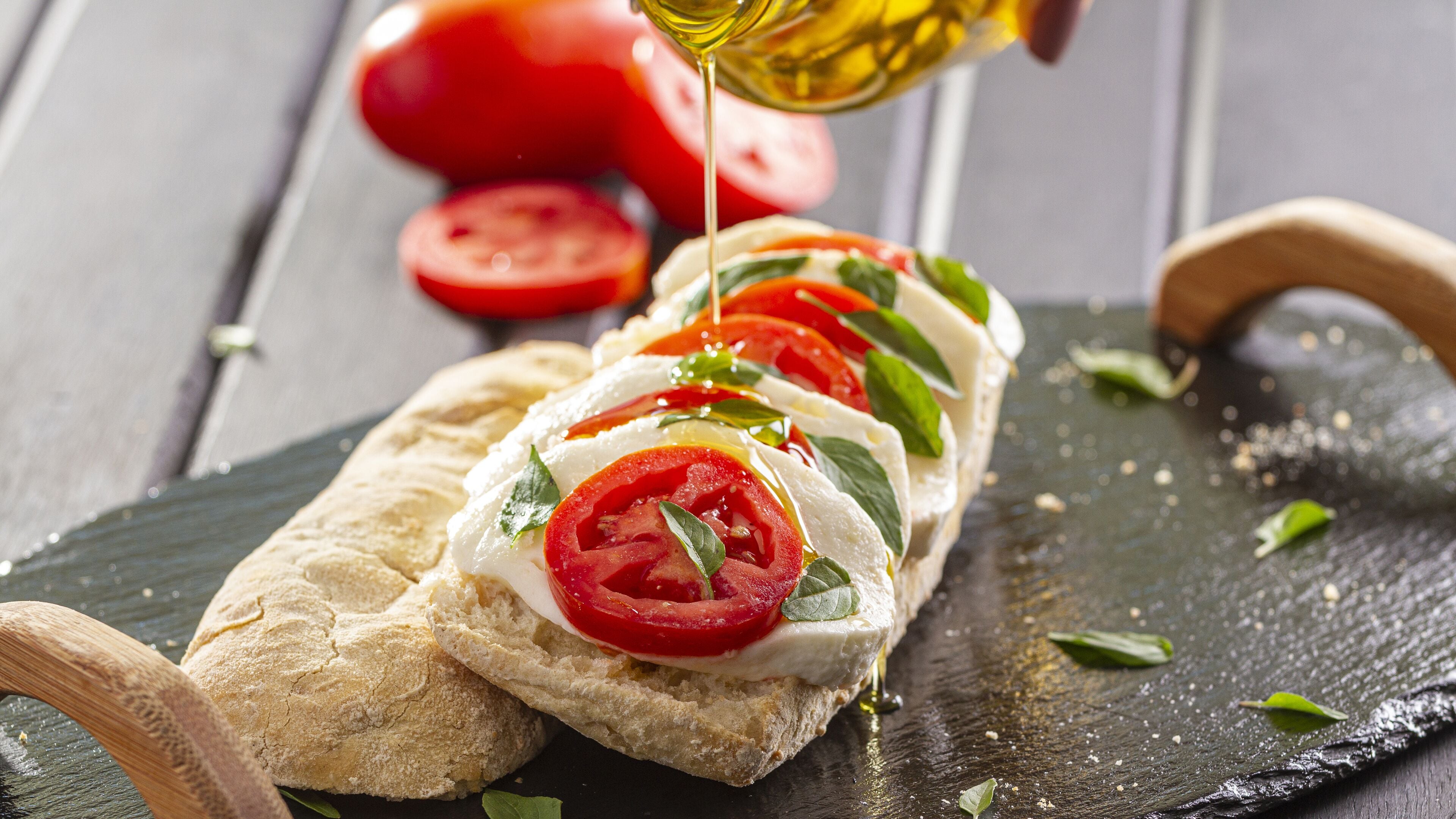 A bruschetta with tomatoes and basil on a slate board.