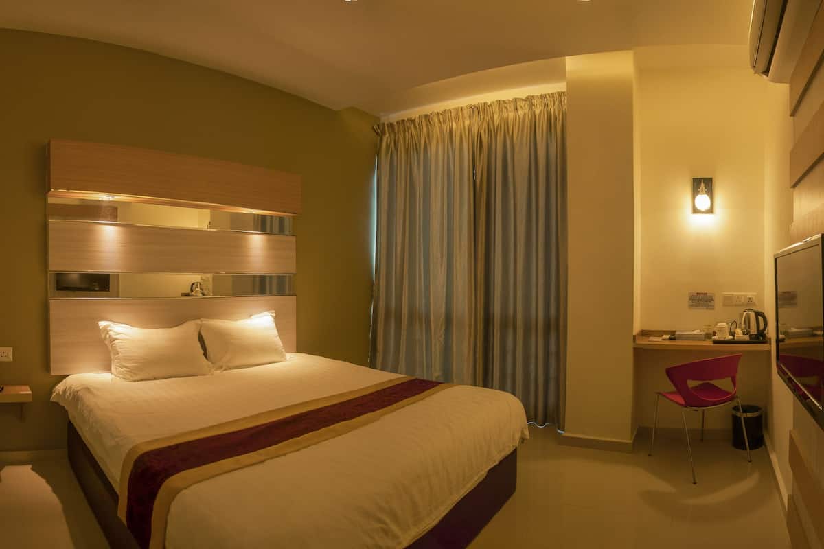 A hotel room with a bed, a desk, a chair, a TV, and a curtain.