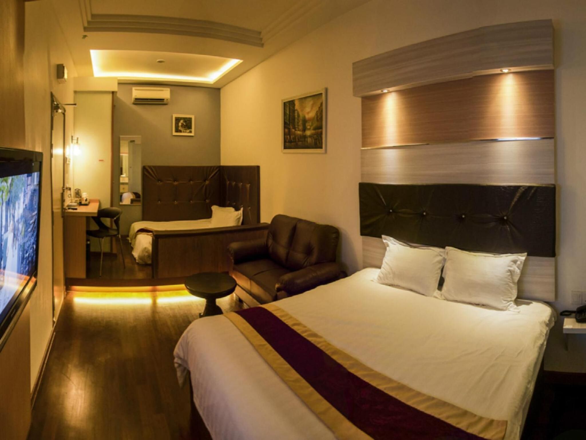 A hotel room with a large bed, a desk, a chair, and a television.
