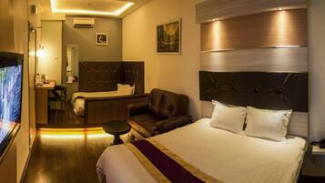 A hotel room with a large bed, a desk, a chair, and a television.