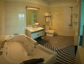 Une salle de bain avec un carrelage à motifs géométriques, une baignoire, un lavabo, des toilettes et une douche.