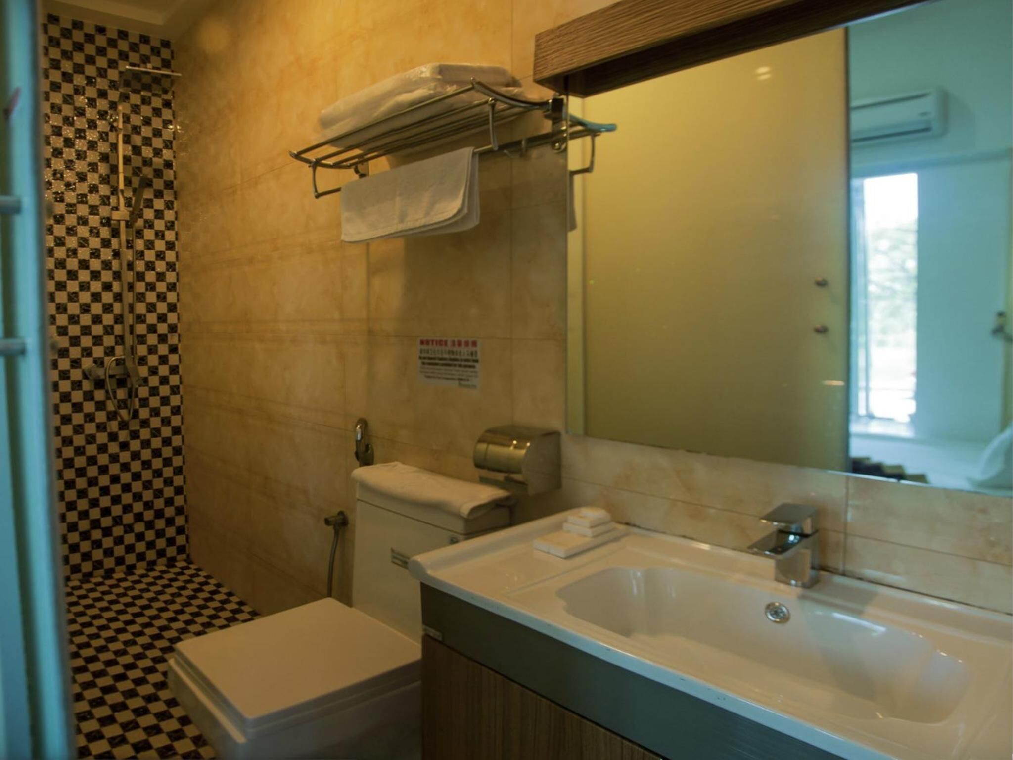 A bathroom with a checkered floor, a shower, a toilet, a sink, and a towel rack.