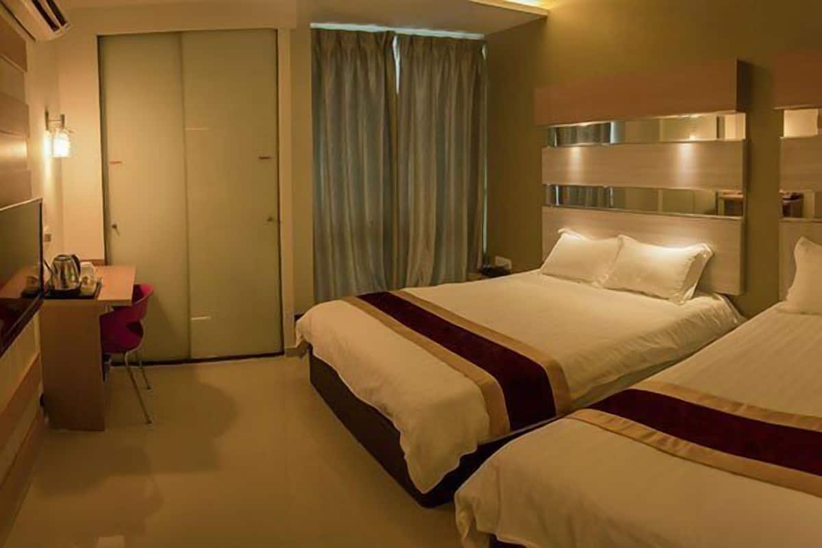 A hotel room with two beds, a desk, a chair, and a television.