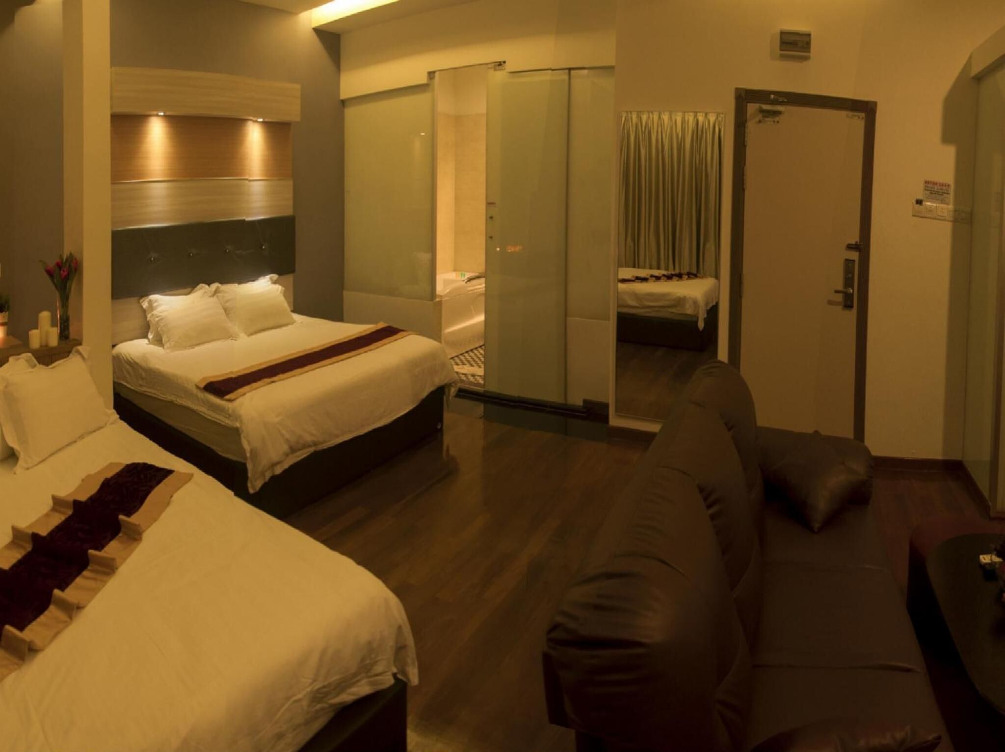 Een hotelkamer met een groot bed, een bank en een glazen scheiding.
