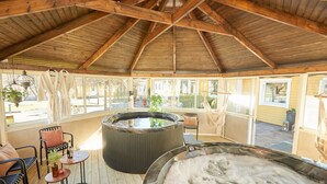 Un espace spa comprenant deux bains à remous, des poutres en bois au plafond et un coin salon avec des chaises et une table.