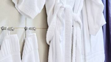 Un baño con toallas y bata blanca colgadas en un perchero.