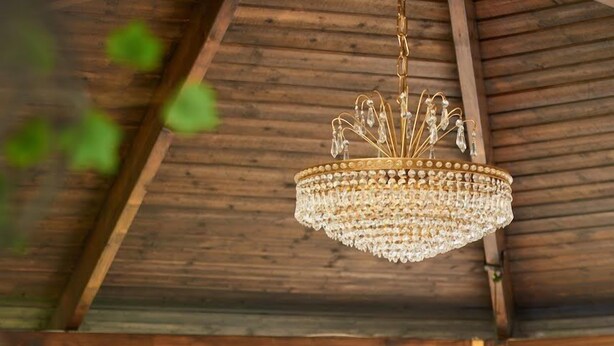 Un plafond en bois orné d’un lustre suspendu, un hamac et un jacuzzi dans une pièce dotée de grandes fenêtres.