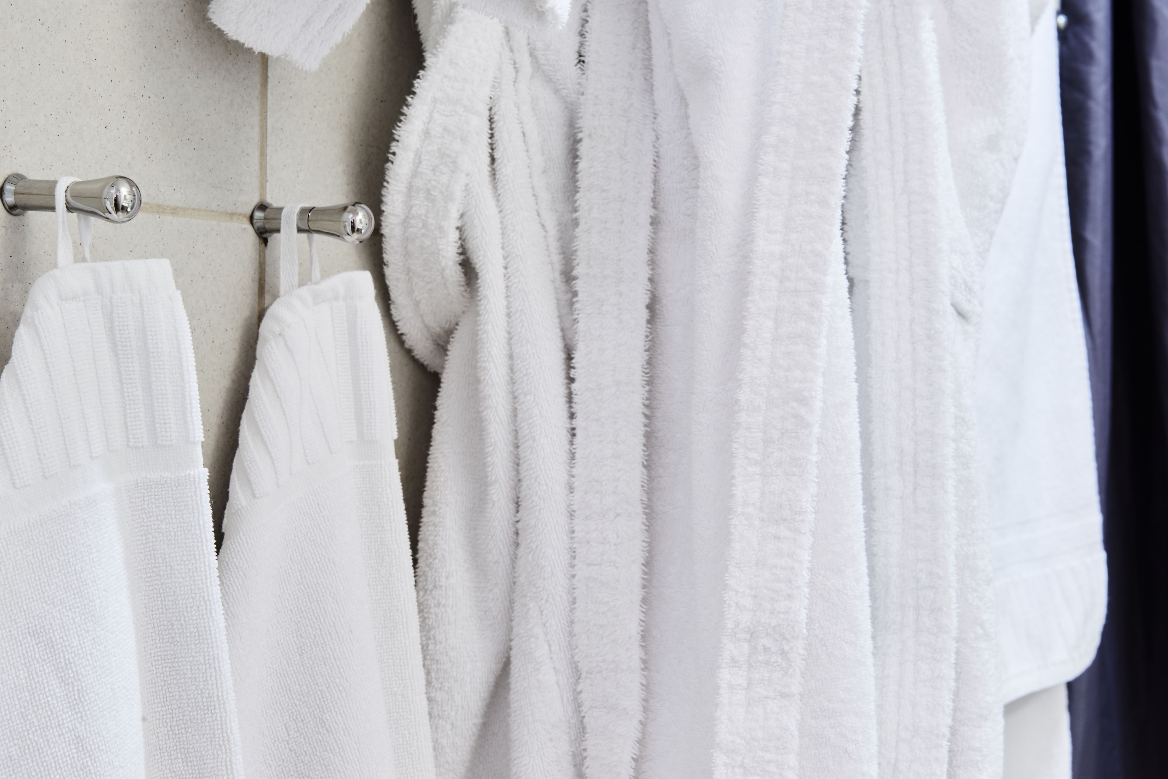 A rack with white towels and a white robe hanging on it.