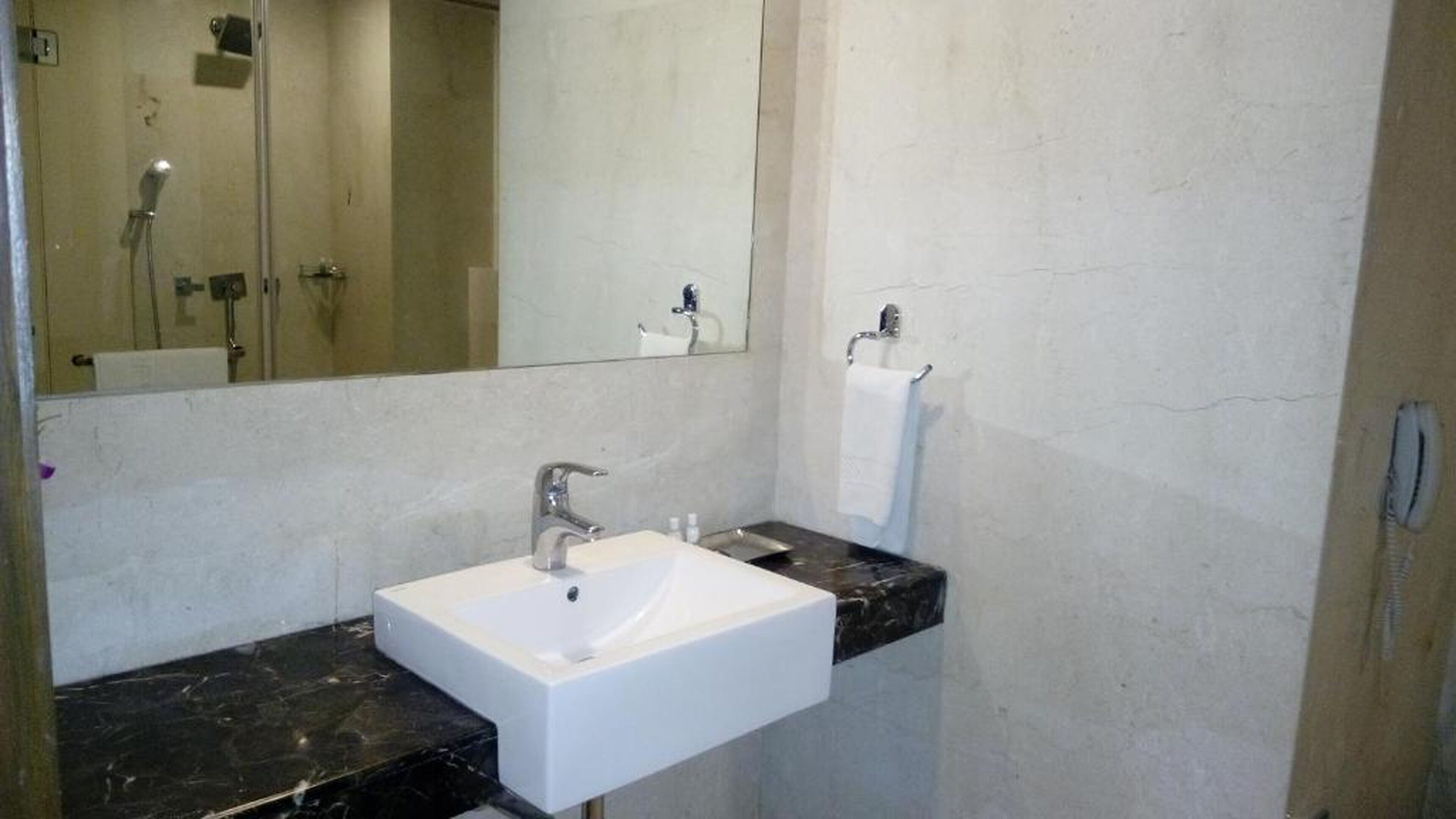 A bathroom with a white sink, a mirror, and a towel rack.