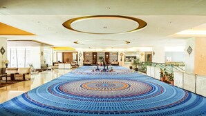 A spacious lobby with a patterned carpet, a reception desk, and a staircase. - VW Canyon (Raipur)