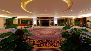 A spacious lobby with a circular patterned carpet, large green plants, and a modern ceiling design. - VW Canyon (Raipur)