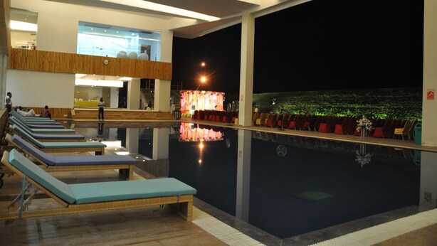 A pool area with lounge chairs and a bar area with chairs. - VW Canyon (Raipur)