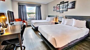 A hotel room with two beds, a desk with a computer, a chair, and a large window with curtains. - Hôtel L'Empress (Rimouski)