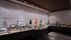 A buffet setup with various food stations and decorative vases. - SK Premium Park (New Delhi)