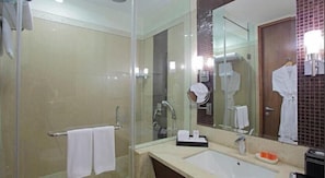 A modern bathroom with a glass shower enclosure, a sink with a mirror, and a towel rack. - SK Premium Park (New Delhi)