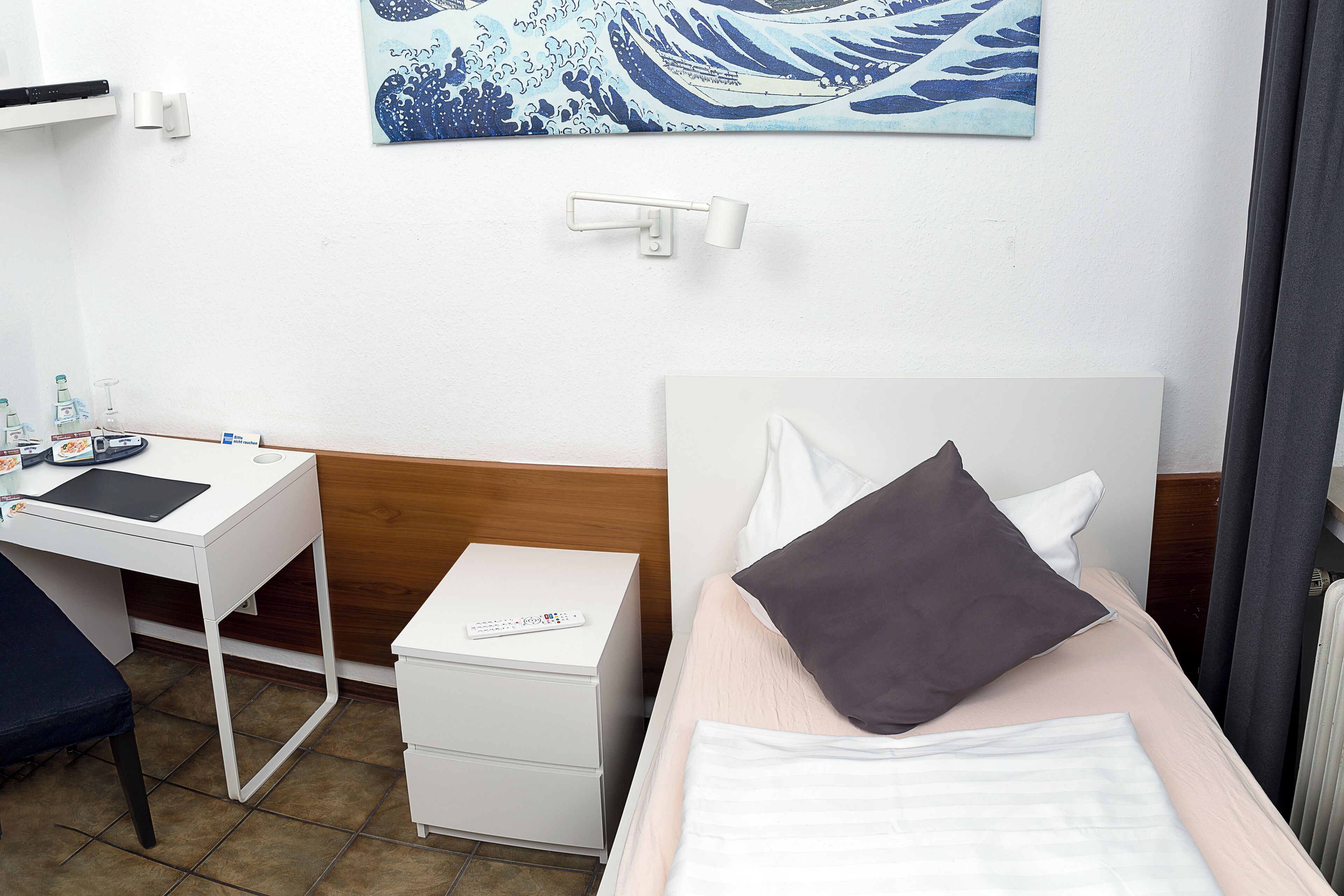Ein Hotelzimmer mit Bett, Schreibtisch und Nachttisch.