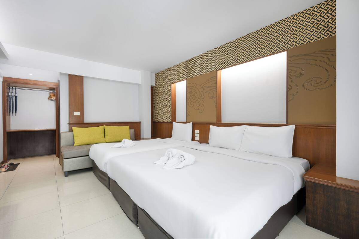 A hotel room with a large bed, a bedside table, a nightstand, and a wardrobe.