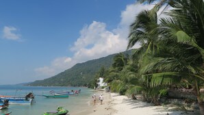 A beach with boats, a jet ski, and palm trees. - Family House Resort (Ko Pha-ngan)