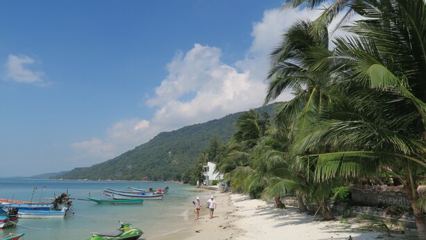 A beach with boats, a jet ski, and palm trees. - Family House Resort (Ko Pha-ngan)