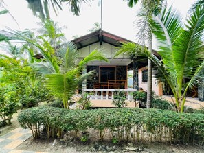 A house with a balcony, surrounded by lush greenery and palm trees. - Family House Resort (Ko Pha-ngan)