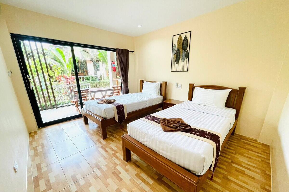 Quarto de hotel com duas camas, varanda e uma pequena mesa.