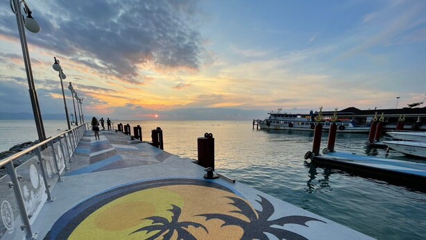 A pier with a sunset view, featuring a palm tree design on the walkway. - Family House Resort (Ko Pha-ngan)