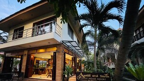 A two-story building with a balcony, a sign reading "Family House Resort Koh Phangan", and a tropical garden with palm trees. - Family House Resort (Ko Pha-ngan)