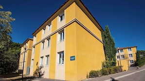 A yellow multi-story building with a sign indicating 'BATHROOM C'. - Comfort Aparthotel Aix Le Tholonet (Le Tholonet)