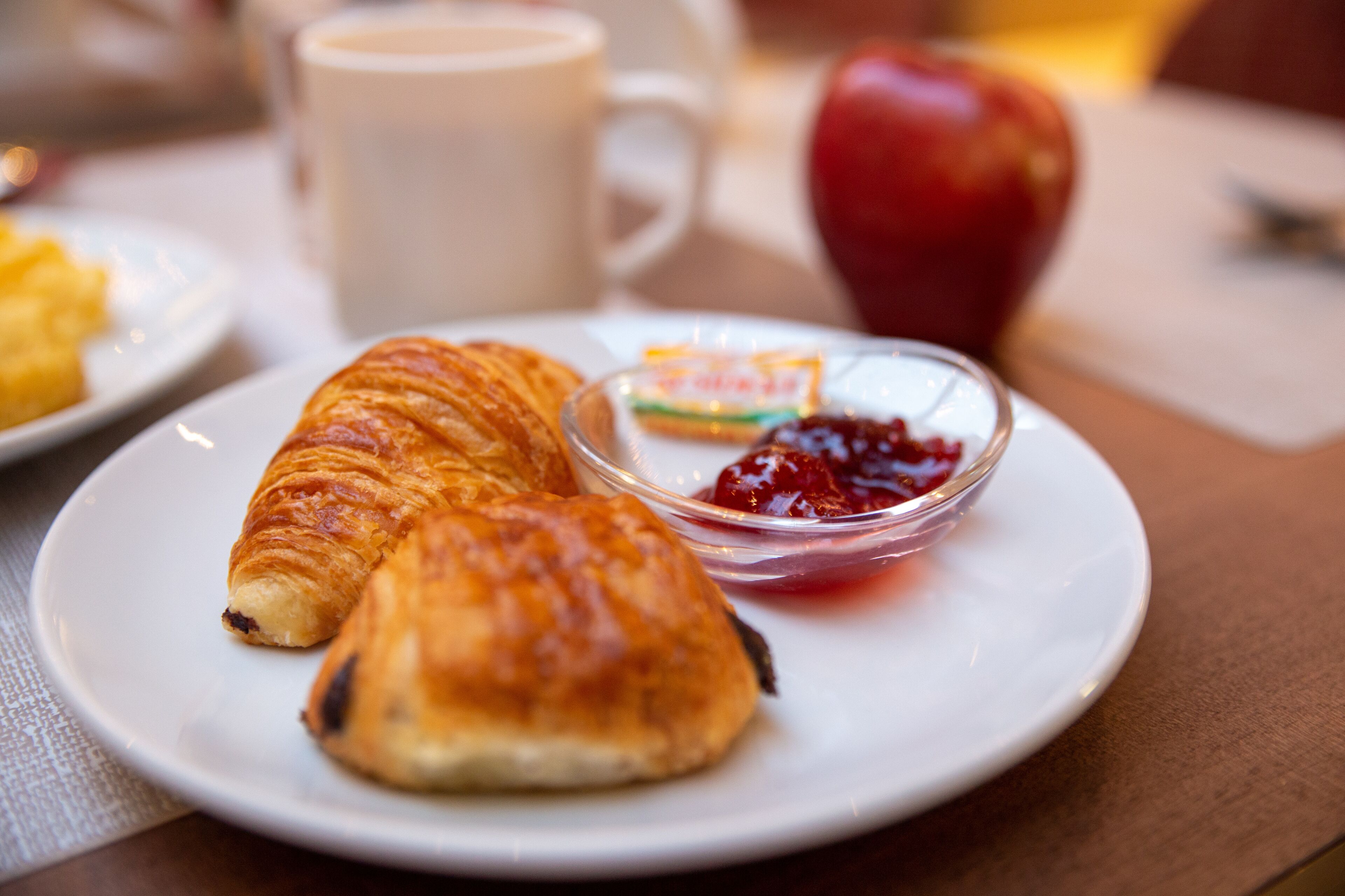 Une assiette avec des croissants et un petit bol de confiture.