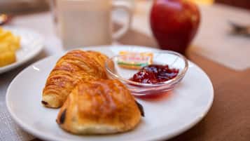Une assiette avec des croissants et un petit bol de confiture.