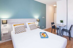 Une chambre d’hôtel avec un lit, des tables de chevet, un bureau et une chaise.