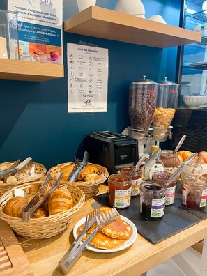 Un buffet de petit-déjeuner avec des croissants, des confitures et une machine à café.
