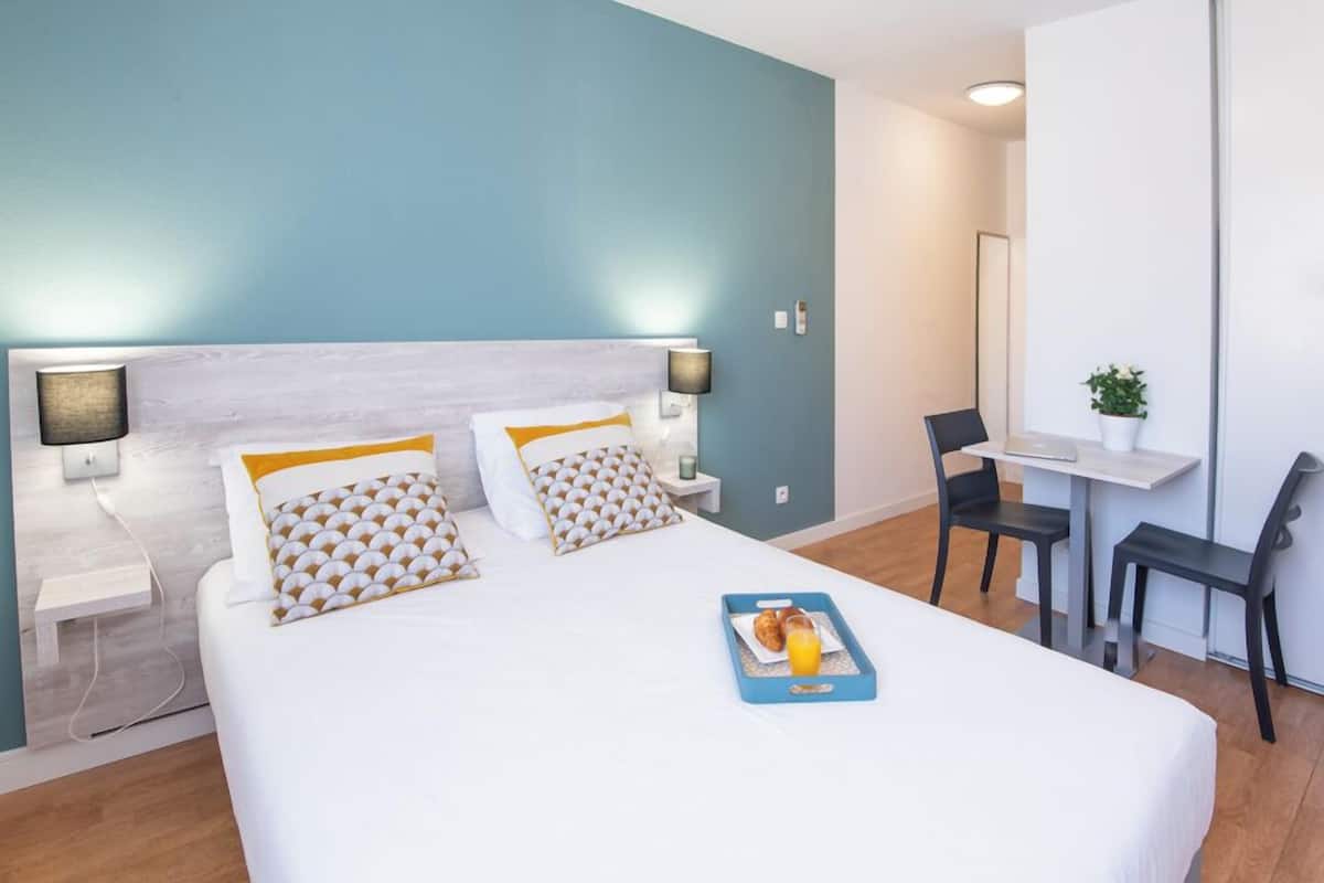 Ein Hotelzimmer mit einem Bett, Nachttischen, einem Schreibtisch und einem Stuhl.