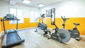 Une salle de sport équipée de tapis de course, d’un vélo elliptique et d’un vélo d’appartement.