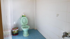 A small bathroom with a toilet, a sink, and a shower area. - Sunny Resort (Phu Quoc)