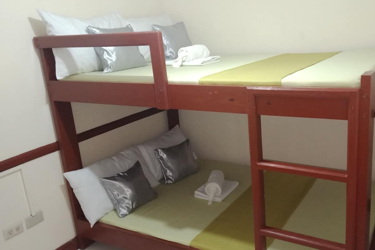 A bunk bed with two levels, each with pillows and a blanket.