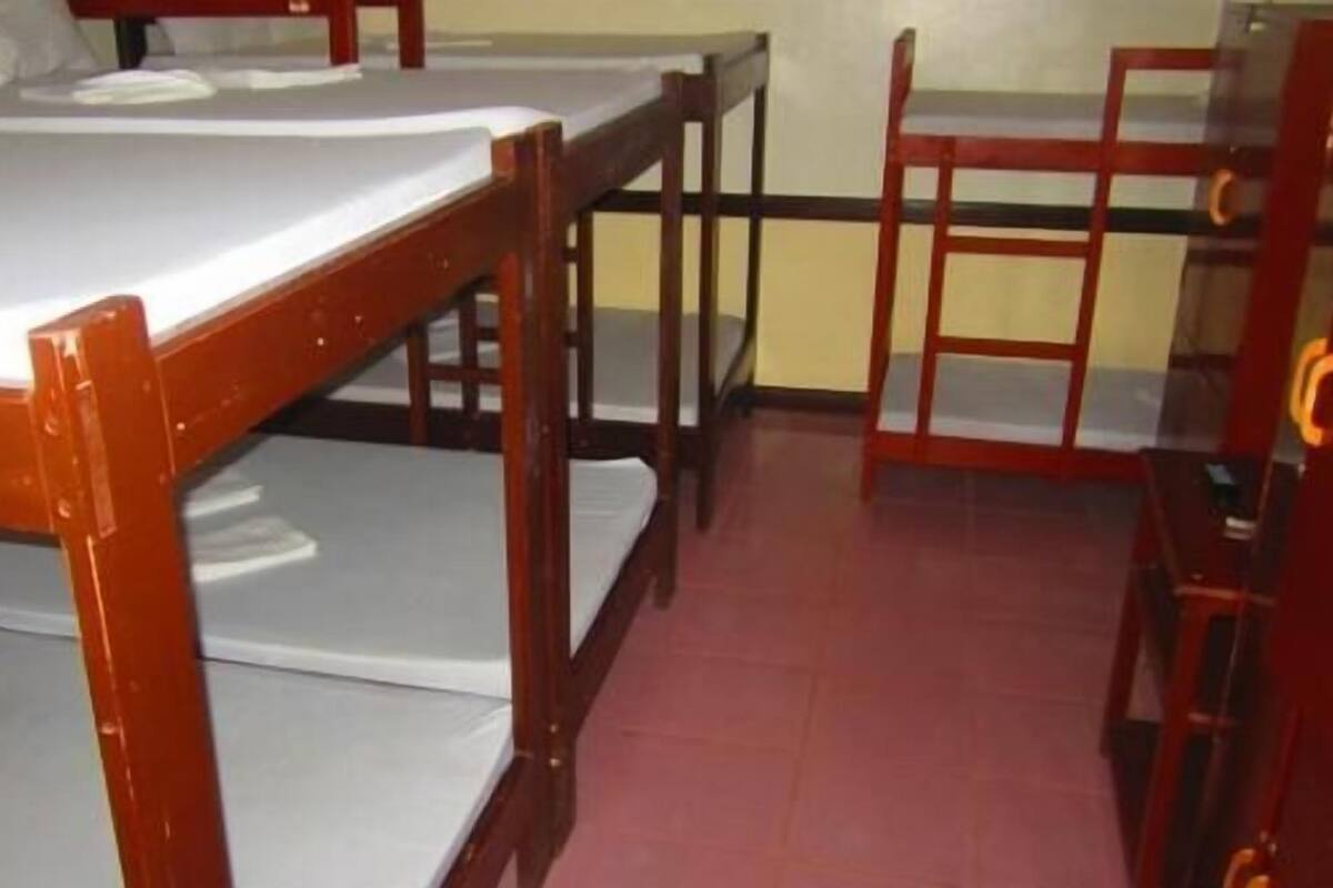 A dormitory room with bunk beds and a single chair.